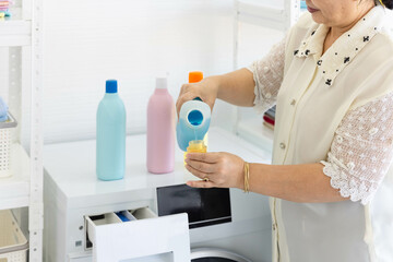 senior woman housework pouring detergent in the bottle cap
