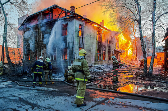 Firefighters extinguish a fire in a two-story wooden house