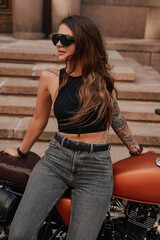 Fototapeta na wymiar Slim female biker posing with old fashioned bike outdoors