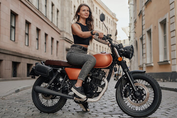 Plakat Brown haired woman riding old fashioned motobike outdoors
