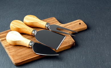 Cheese cutter set with wooden board. Group of cheese knives on the cutting board.Top view