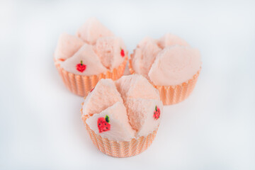 fluffy soft pink cupcake with strawberries painted in orange paper cup on white floor