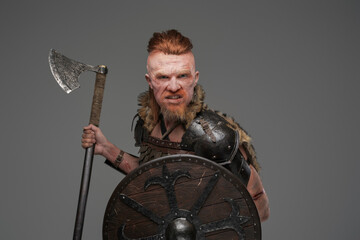 Mad redhead viking with shield and axe isolated on gray