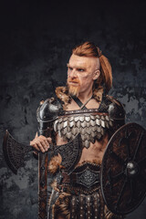 Viking posing with shield and axe against dark background