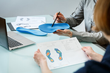 Doctor consulting patient on custom orthotic insoles in a clinic for a personalised custom fit. - obrazy, fototapety, plakaty