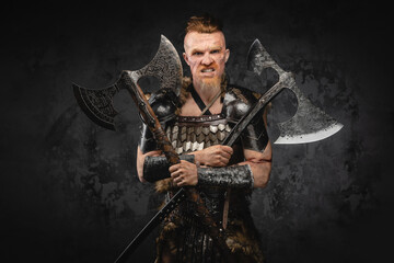 Violent viking with dual axes against dark background