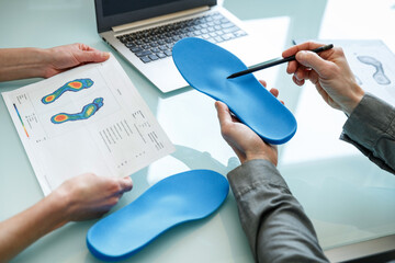 Doctor consulting patient on custom orthotic insoles in a clinic for a personalised custom fit. - 485391222