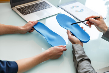 Doctor consulting patient on custom orthotic insoles in a clinic for a personalised custom fit.