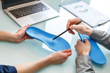 Doctor consulting patient on custom orthotic insoles in a clinic for a personalised custom fit.