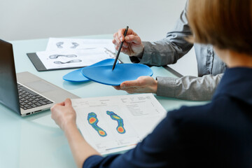 Doctor consulting patient on custom orthotic insoles in a clinic for a personalised custom fit. - 485391259