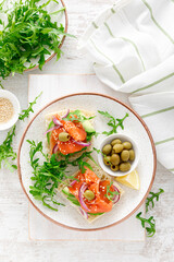 Open sandwiches with salted salmon, avocado, olives and arugula. Breakfast. Top view