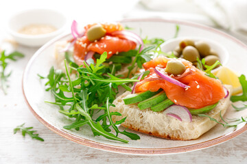 Open sandwiches with salted salmon, avocado, olives and arugula. Breakfast