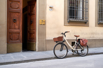 Fototapeta na wymiar Bicycle with basket and brown leather bag or pannier parked on the old street in Italy