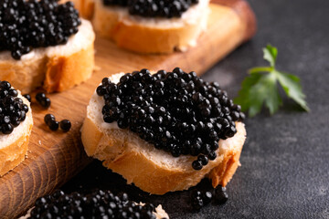 Slices of bread with black caviar on rustic dark background