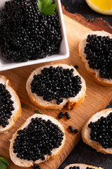 Slices of bread with black caviar on rustic dark background