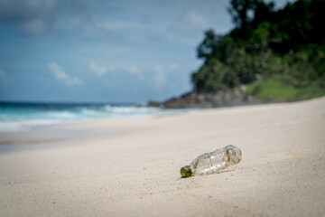 plastic rubbish washed up from ocean on sandy white beach gentle waves in paradise mountain background pollution