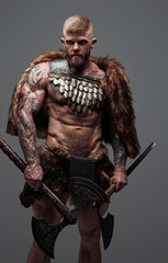 Naklejka premium Furious viking dressed in fur and armor holding two axes