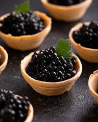 Tartlets with black caviar on rustic background