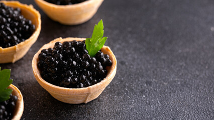 Tartlets with black caviar on rustic background