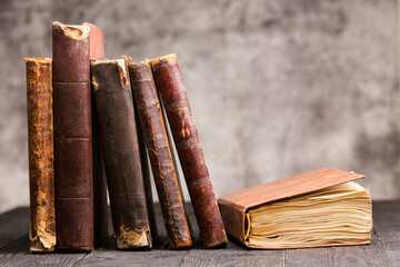 Vintage leather books stack on old rustic wooden surface