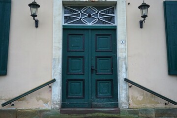 Alte grüne Haustür aus Holz von rosafarbener Hausfassade im Winter
