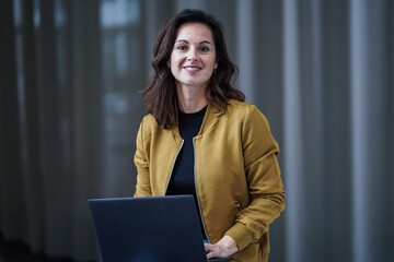 happy smiling remote working woman in casual outfit sitting in cross legs pose with her laptop or...