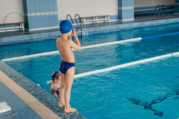 A group of boys and girls play and learn to swim in a modern swimming pool. Development of children's sports. Healthy parenting and promotion of children's sports.