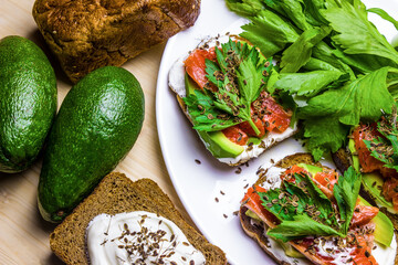Sandwiches with avocado, trout and sour cream, sprinkled with spicy dill. Celery leaves.