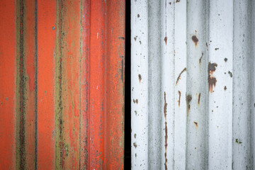 Rusty metal texture background. Red and white corrugated steel sheets with scratches and corrosion stains. Old worn iron garage door detail. Rough, rustic and grunge. Close up, copy space