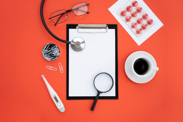 Top view, medical accessories on a red background. Tablet for notes, stethoscope, glasses, pills, medicines, coffee cup, magnifying loupe. Flat lay, mockup