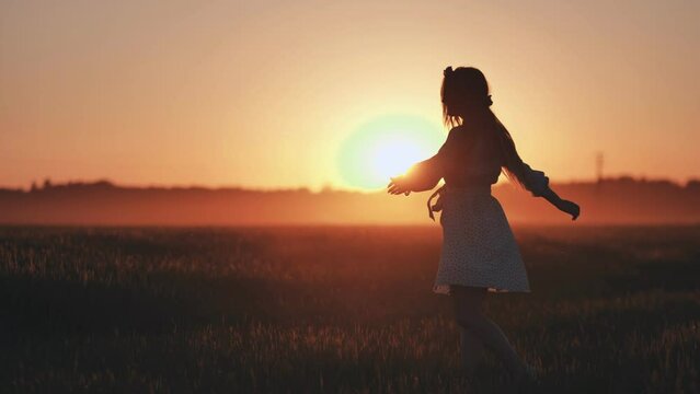 A silhouette of a young Ukrainian girl circling at sunset in the summer.
