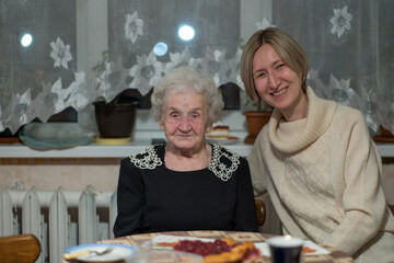 An old woman at the table with her adult daughter.