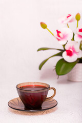 Flower tea karkade. Delicious herbal tropical drink on a bright table. A cup of pink tea from dry hibiscus petals, a natural medicinal drink against the background of fern leaves. Tropical morning.