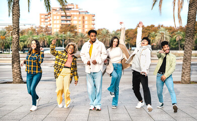 Multicultural friends walking at Barceloneta waterfront on funny moves - Happy guys and girls having fun by beach broadwalk street on party mood - Travel vacations life style concept - Bright filter