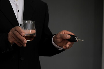drink driving with hand holding key and alcohol drink on grey background stock photo