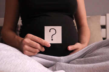 Pregnant woman holding cards with the inscription of quastion