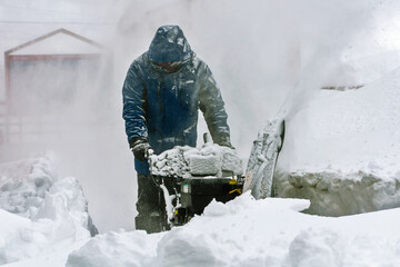 A man cleans the paths from snow after a snowfall with a snowplow. Soft focus.