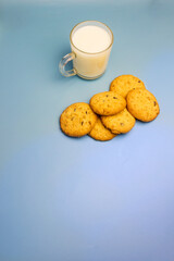Cookies with chocolate shavings and milk in a glass cup, red plaid on a blue background