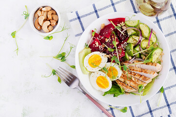 Fototapeta na wymiar Healthy breakfast. Boiled eggs salad with greens, cucumbers, beetroot and grilled chicken fillet and red onion. Lunch. Top view, above