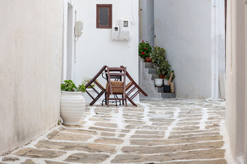 Fototapeta na wymiar Paros island Naoussa village destination Greece. Empty table and chair building, pot with plant.