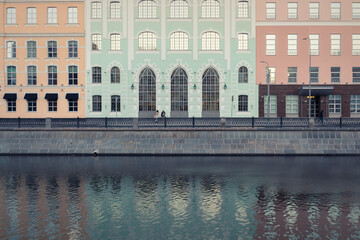 A river in front of an embankment against a colorful facade by autumn day