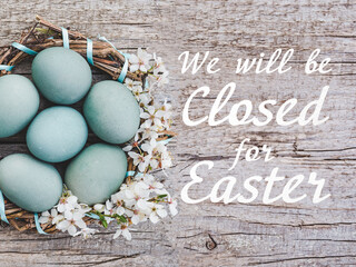 Signboard with the inscription We will be closed for Easter. Easter eggs painted with colorful...