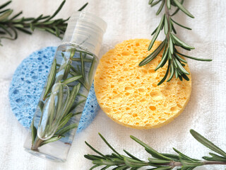 Transparent bottle with natural rosemary tonic or flower water or hydralate. Branches of fresh...
