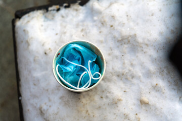 Used protective mask inside a paper coffee cup