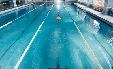 A young man trains and swims in a modern swimming pool. Sports development. Preparation for...