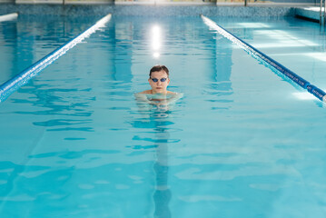A young man trains and swims in a modern swimming pool. Sports development. Preparation for...