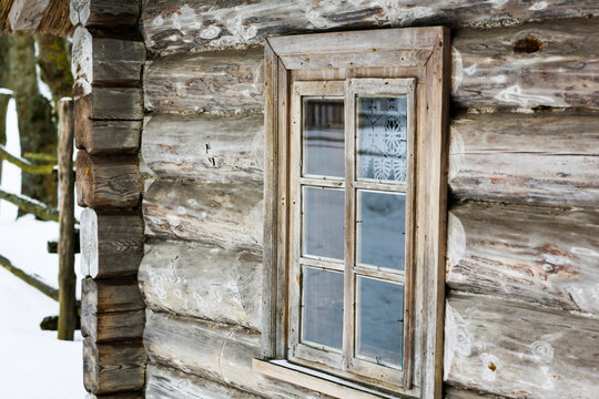 Rustic wooden house made of round logs. Abandoned villages and houses. Ancient window design. Wooden window frame. Snow covered village. Age-old buildings. Professional photography.