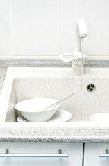 Dishwasher full of dirty dishes. Washable dishes in the sink. Dishes are ready for washing. Water flows from the tap.