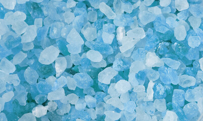 Blue salt crystals as background photo. Closeup blue ice stones lay on a flat surface. Rectangular...