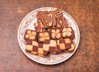 checker cookies in a plate isolated on dark wooden background top view Christmas cookies